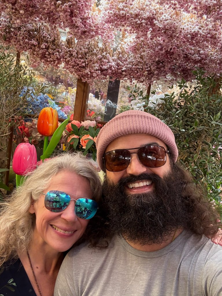 BJ and Val among the flowers — a devotional, conscious-living community tending a garden and a chapel in rural Ohio.