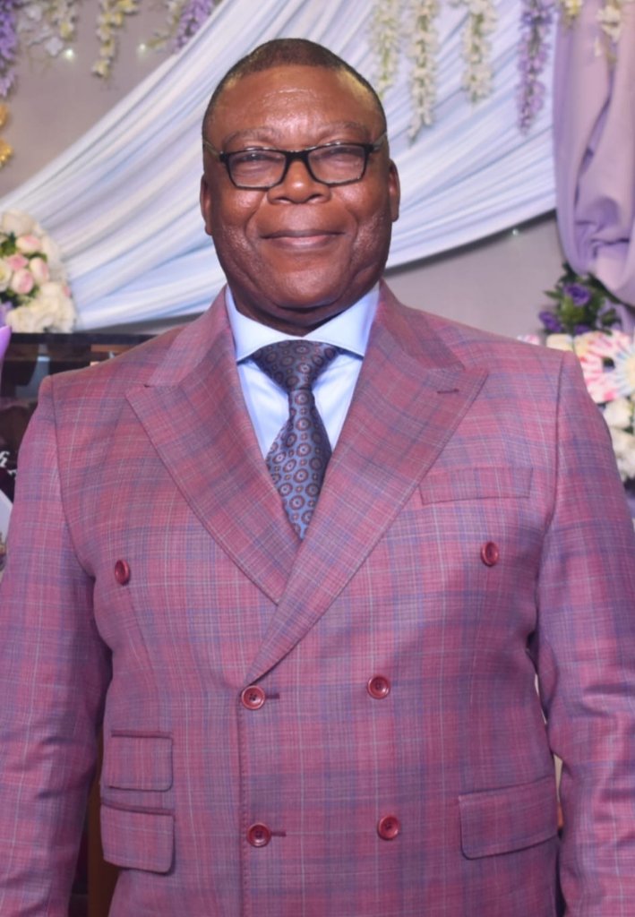 Formal portrait of Dr. David Enow Nsoesie, Co-Founder of Stream Garden TV, wearing a double-breasted plaid suit with glasses