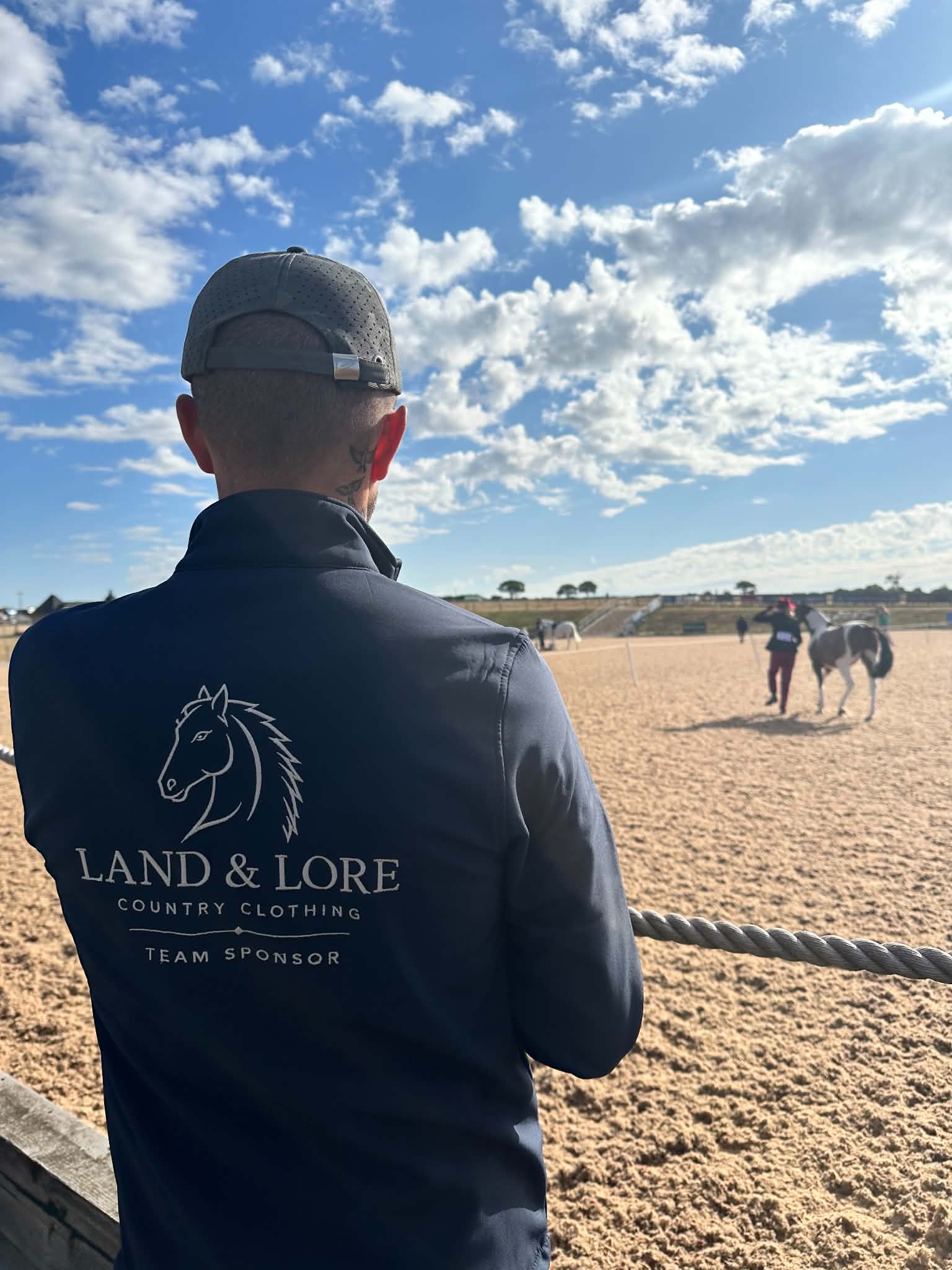 Team sponsor in navy Land & Lore quarter-zip in an equestrian arena