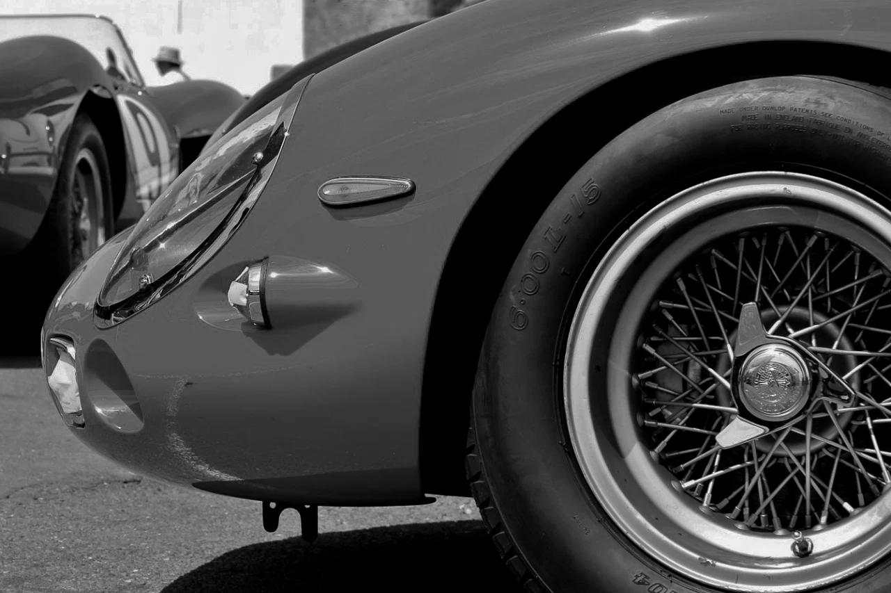A close-up of a wire-spoke wheel and front fender of a vintage racing car