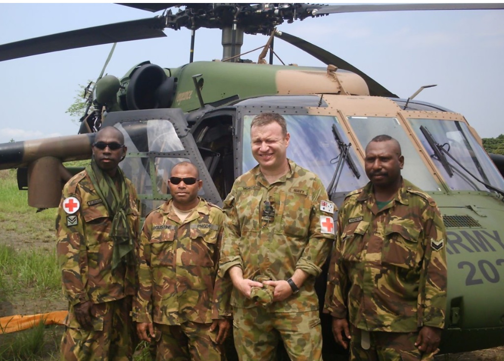 Dr John McHugh with PNG Defence Force and multinational military medical personnel in front of military helicopter