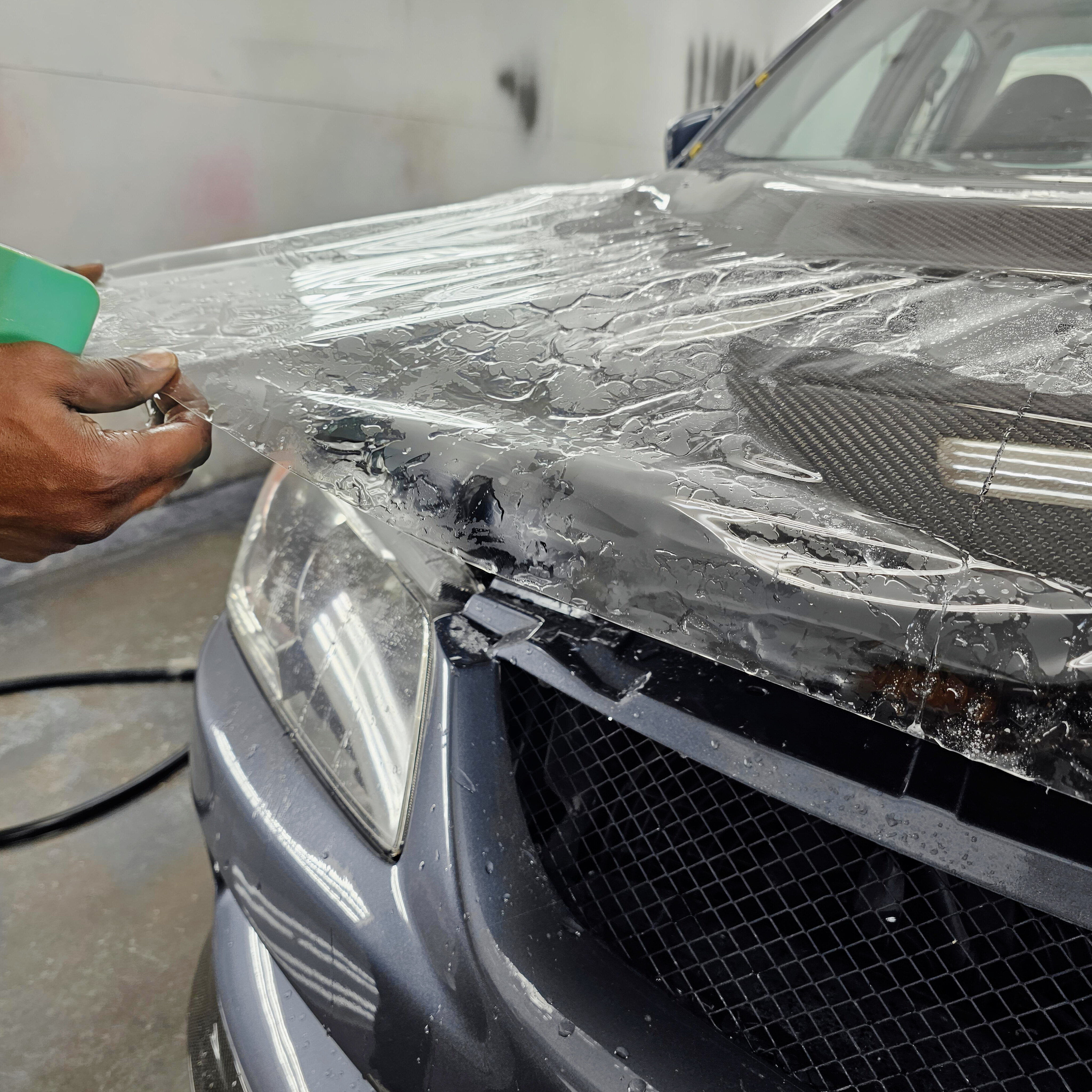 Paint protection film being applied to the hood of a dark grey vehicle at YEG Auto Studio