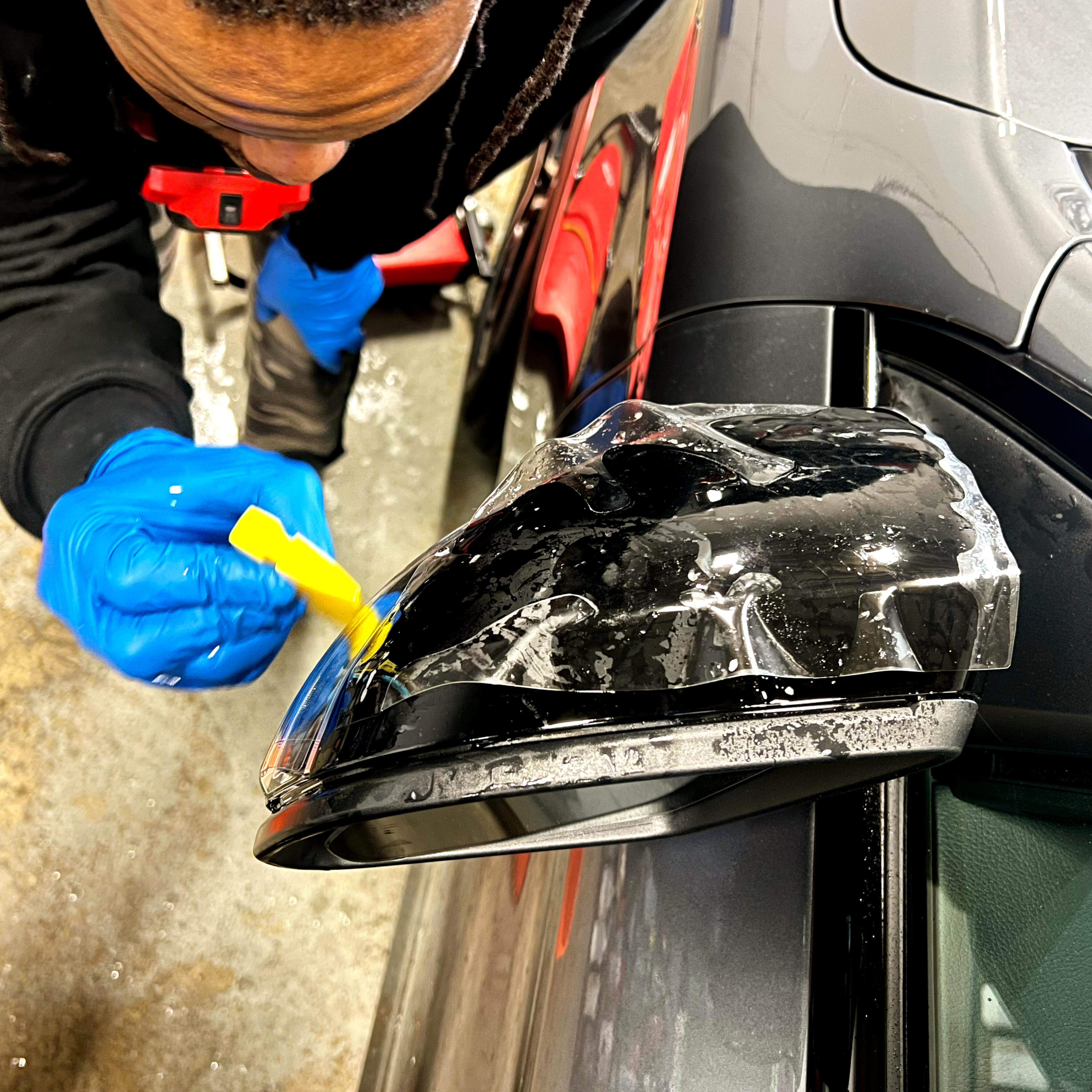PPF being squeegeed onto a side mirror at YEG Auto Studio