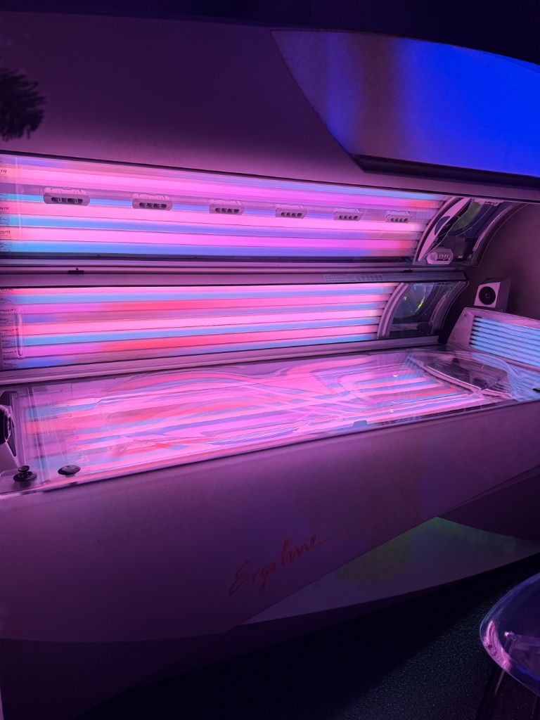 Ergoline tanning bed with pink and blue neon lighting