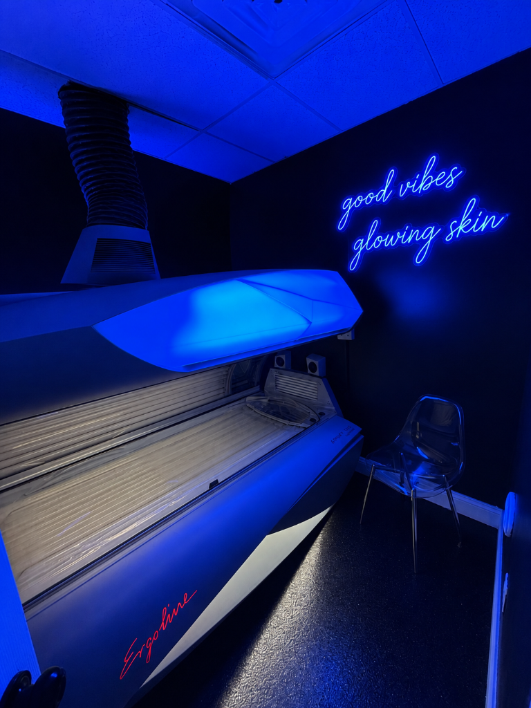 Neon-lit private tanning room with premium bed