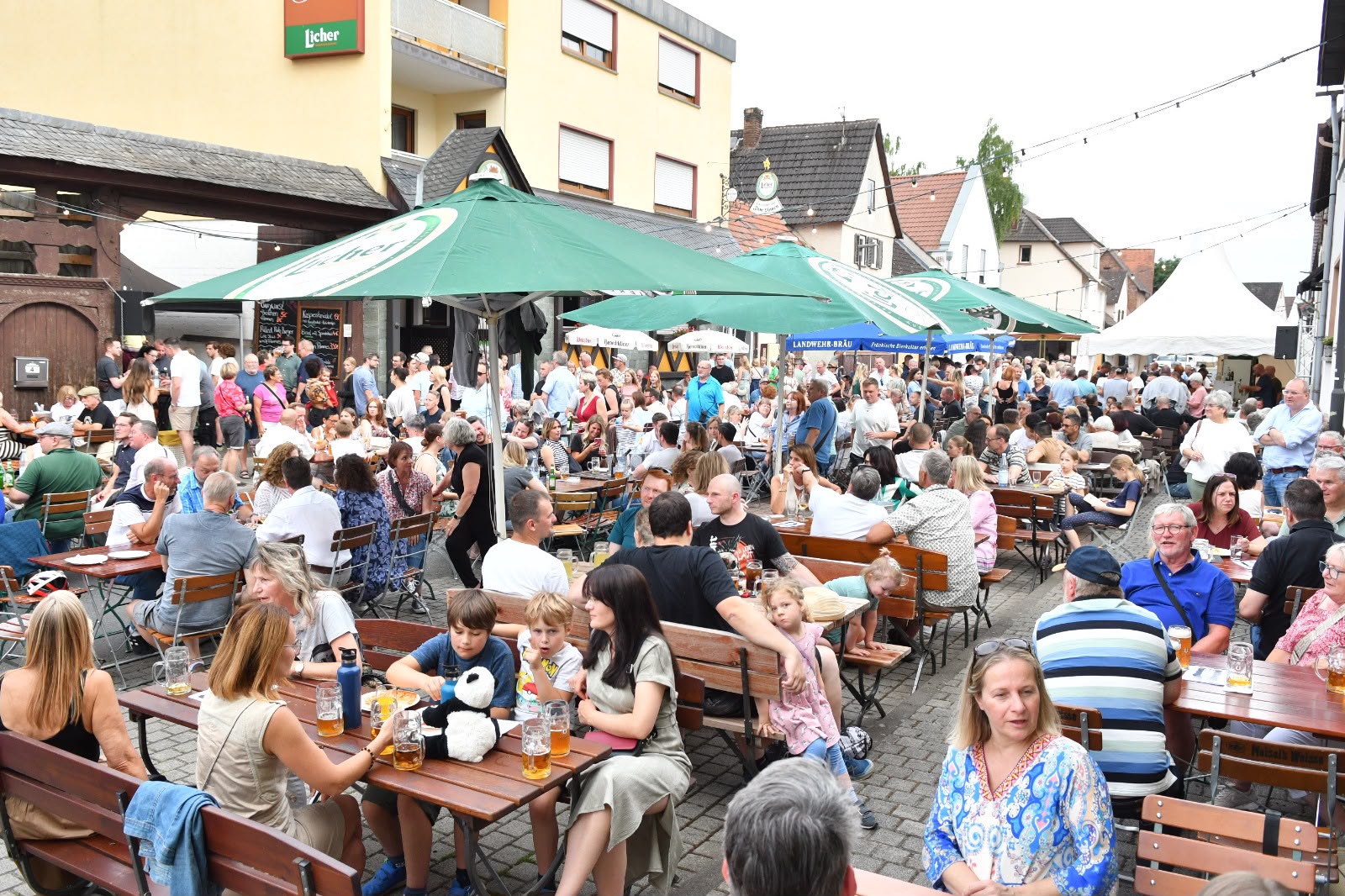 Blick über den dicht besetzten Festplatz mit Sonnenschirmen