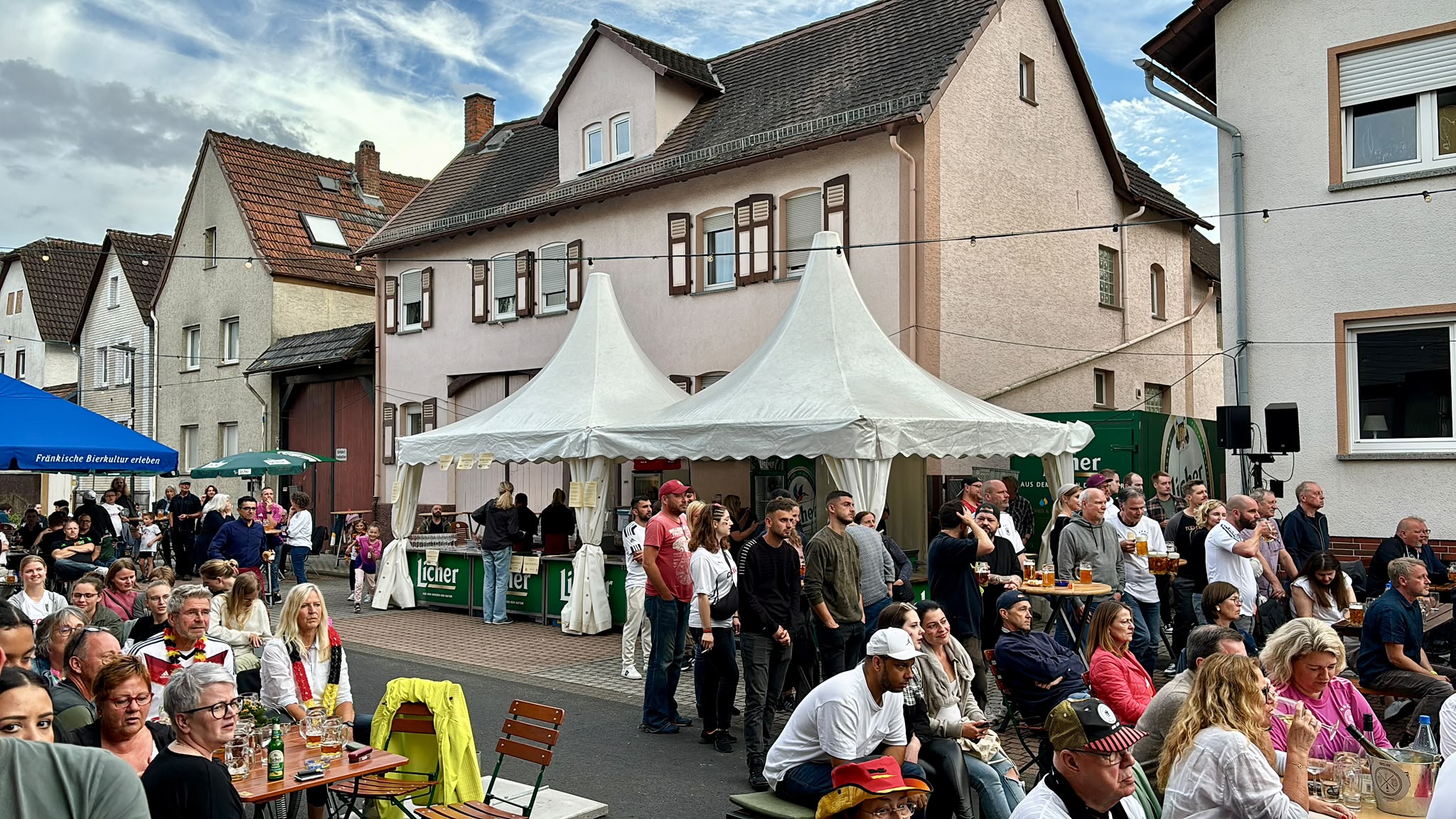 Weiße Festzelte mit dicht besetzten Biergartengarnituren