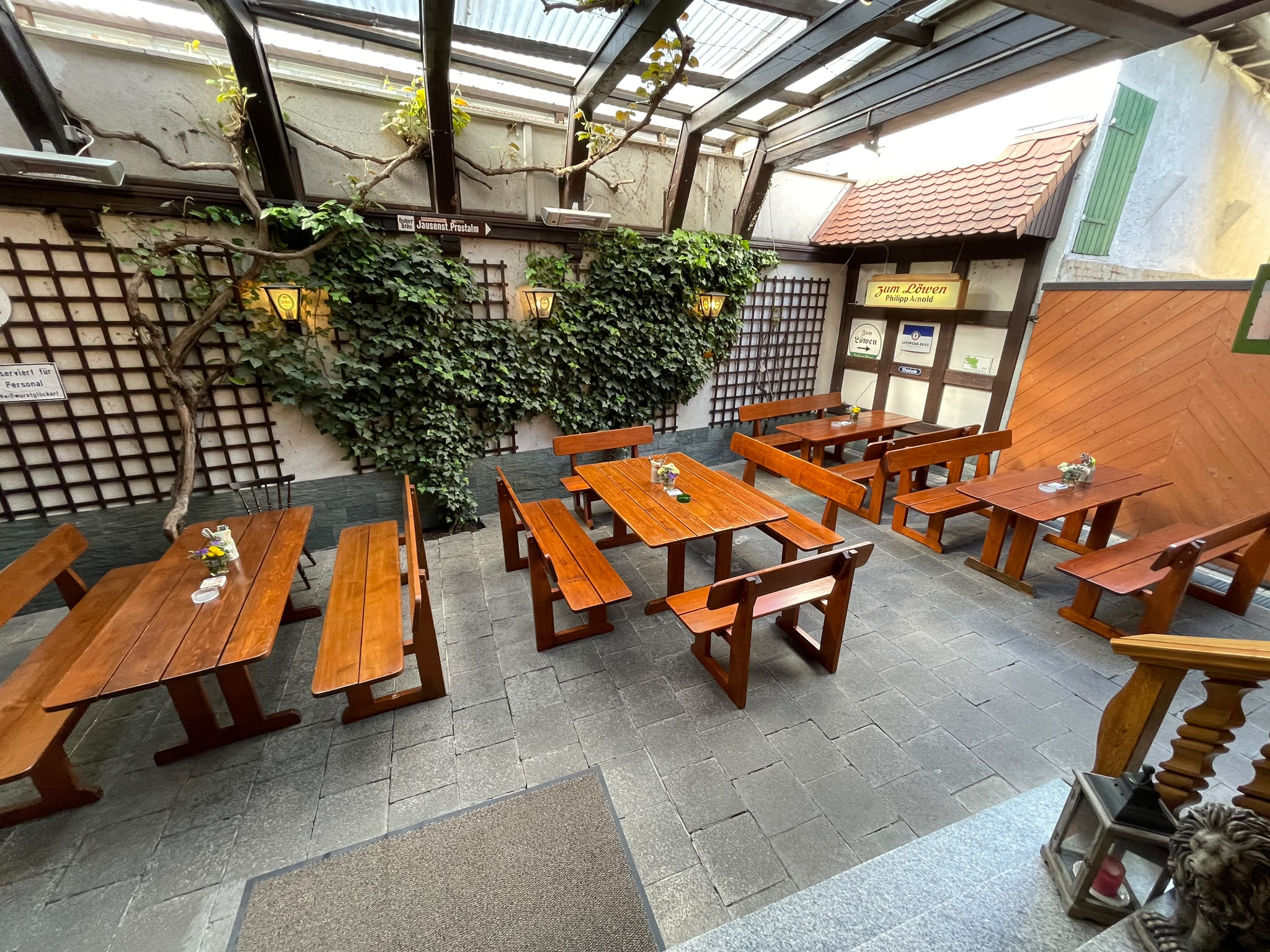 Überdachter Biergarten des Landgasthofs mit Holztischen und Efeuwand