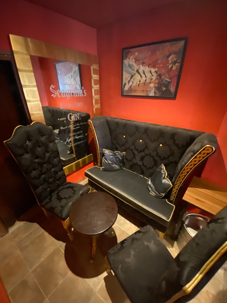 Rincón íntimo de Café Tocado con sillón de terciopelo, espejo y póster de Moulin Rouge