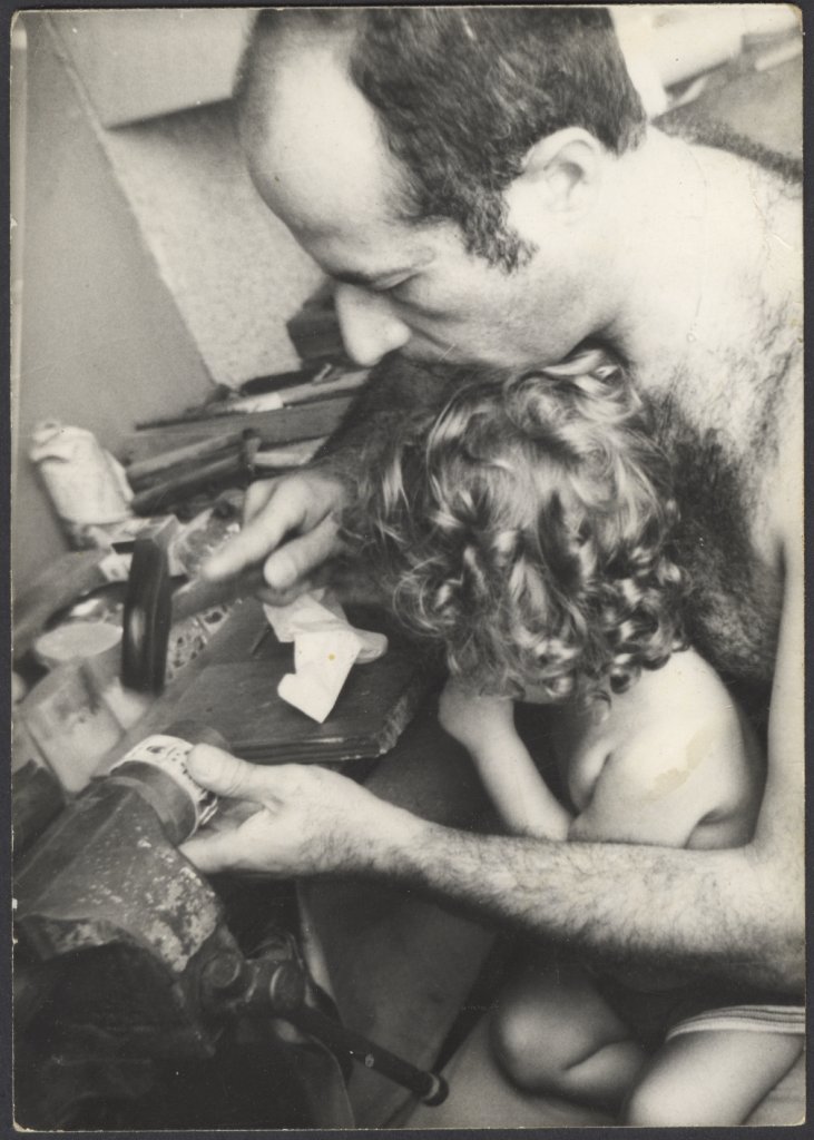 Carmel at his workbench creating a set of 12 Tribes Napkin Holder, with daughter Rachel, circa 1979