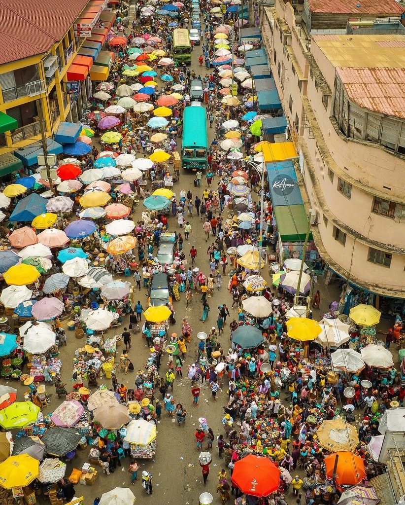 Makola Market in Accra Ghana, a dense sea of colorful umbrellas and crowded stalls on a bright sunny day