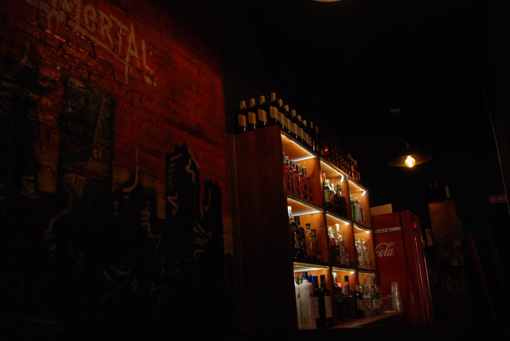 Barra trasera del Bar Immortal con estantería de licores iluminada