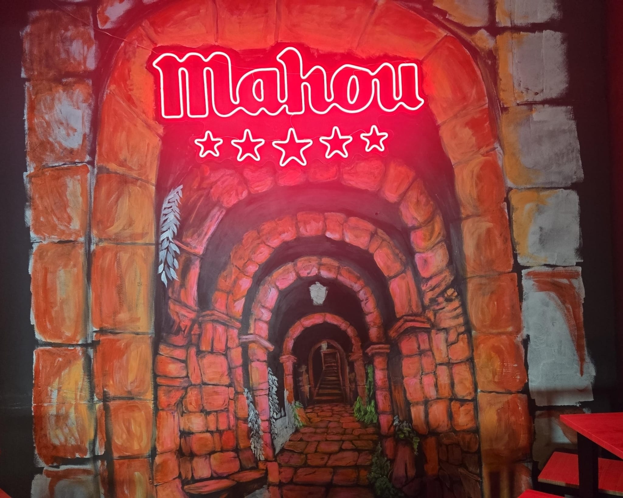 Mural de túnel de piedra con neón rojo de Mahou