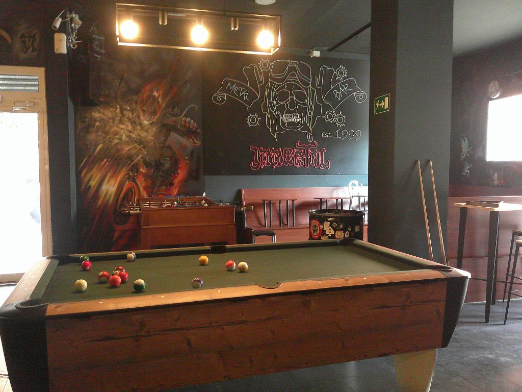 Interior del Bar Immortal con mesa de billar, futbolín y murales