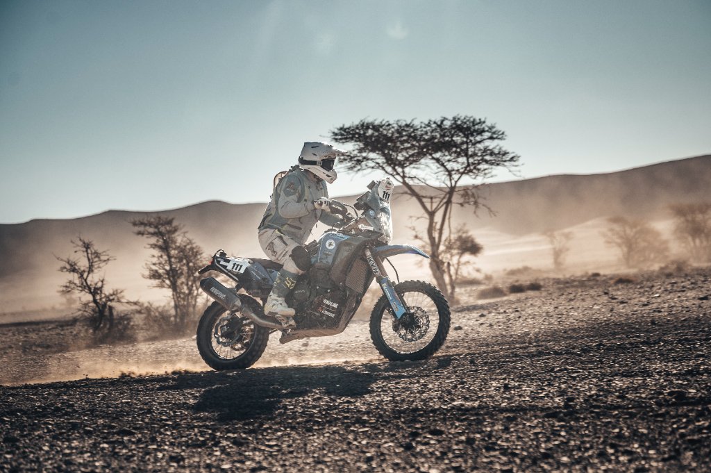 Off-road motorcycle rider in profile crossing a desert landscape