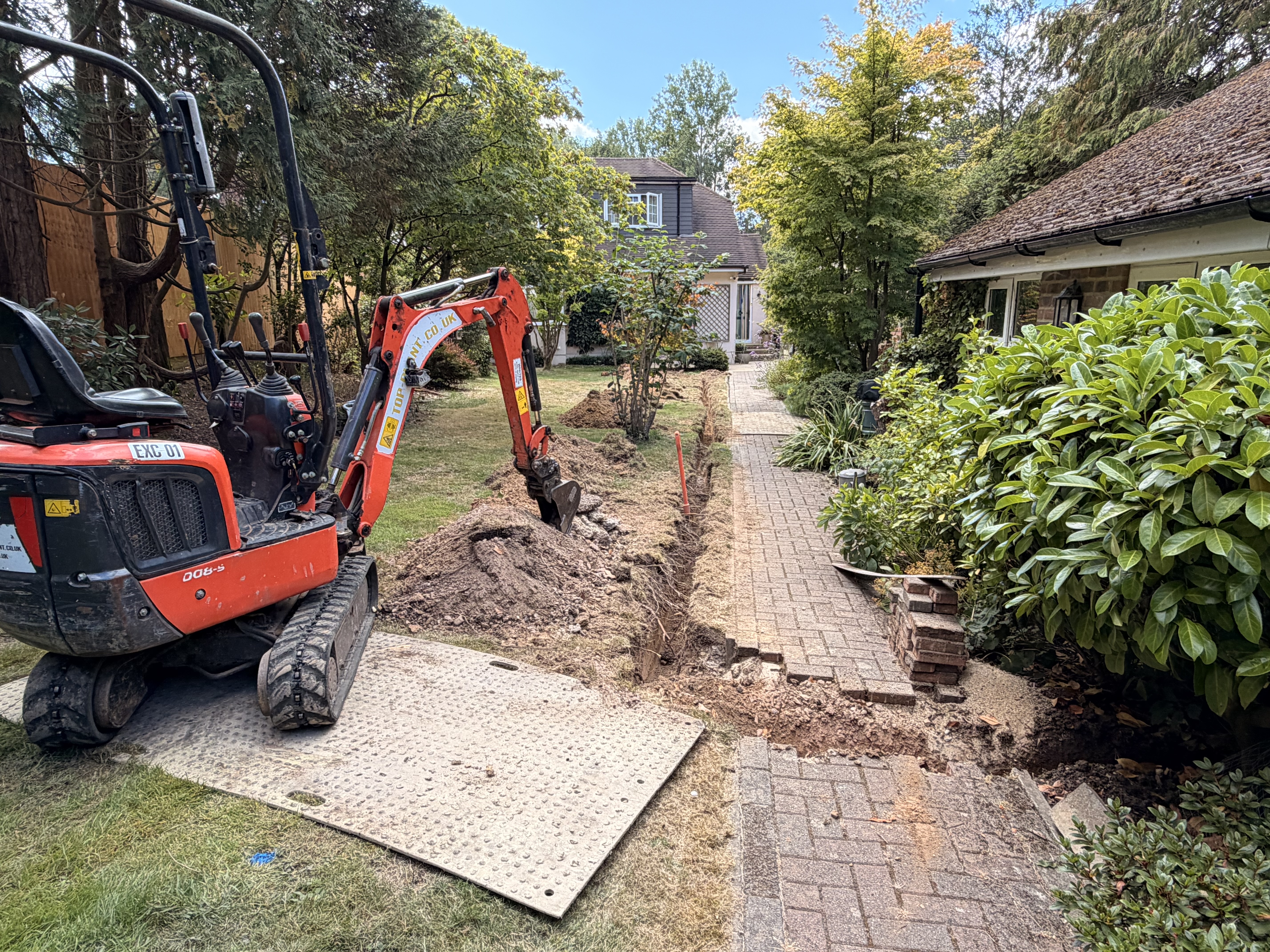 Kubota micro-excavator carrying out utility trenching and drainage installation in a residential garden in Sussex — trenching in Sussex and utility trenching in Sussex by Subsoil Land & Water, drainage and water utility contractors serving Kent and East Sussex
