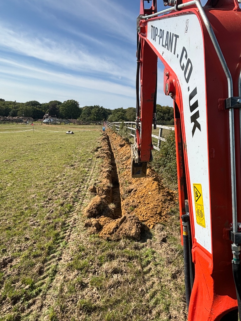 Tracked excavator digging trench for water main installation and water pipe installation on a South East water utilities project by Subsoil Land & Water trenching services contractors