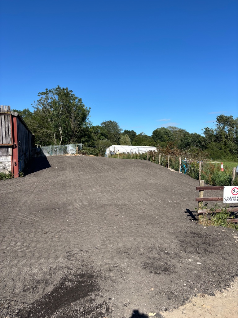 Freshly cleared and graded groundworks site surface prepared for construction by Subsoil Land & Water near agricultural barn in Kent and East Sussex, showing compacted earth and tyre tracks
