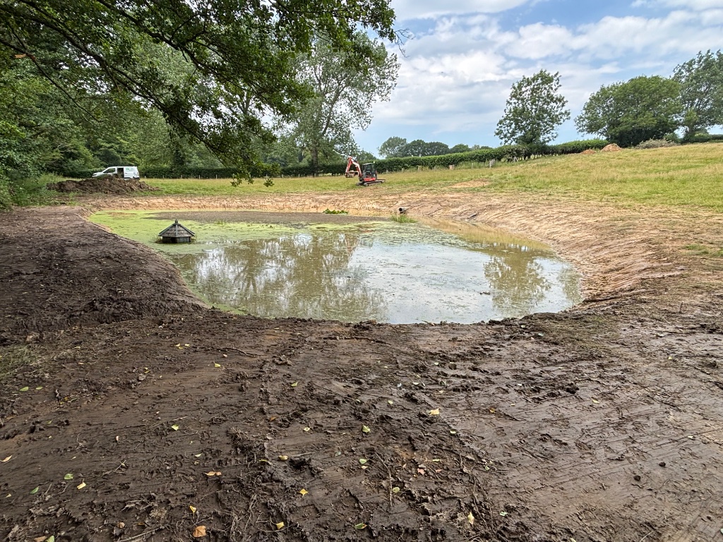 Completed large pond excavation, lake creation and specialist water management project in Battle, East Sussex by Subsoil Land & Water — showing excavated pond with shaped banks, open water and site plant during final ditching and wildlife area creation stages