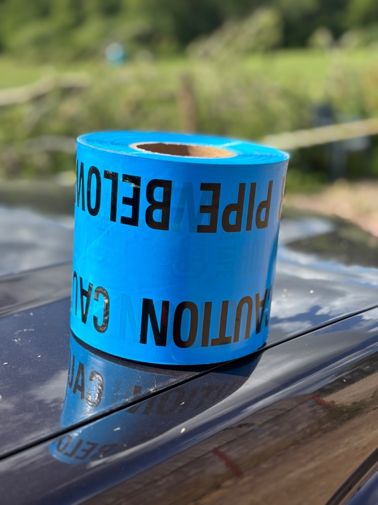 Roll of blue caution water pipe below warning tape used on water main installation and trenching projects by Subsoil Land & Water, water utility contractors in the South East