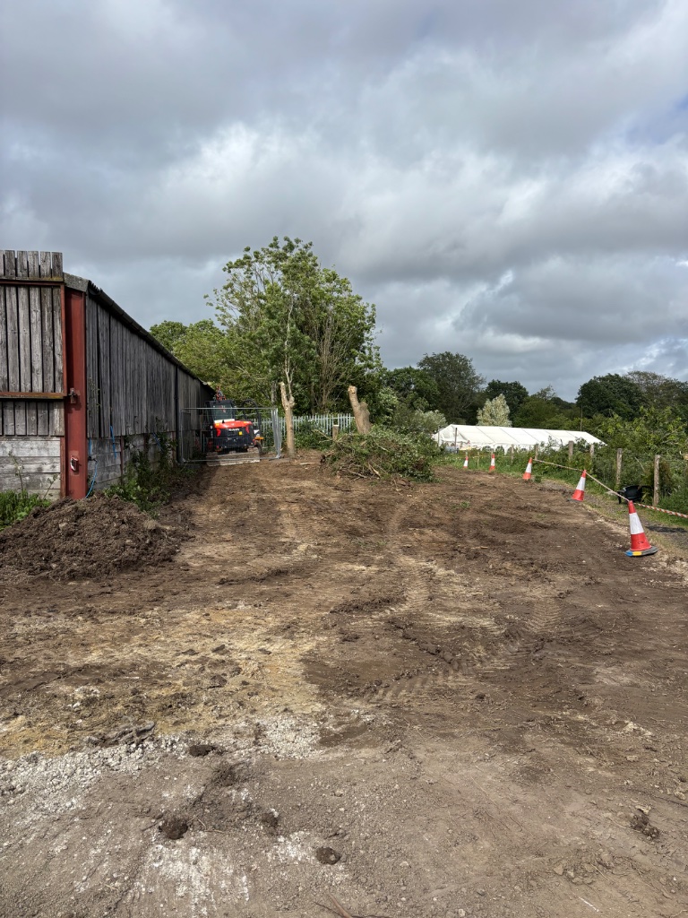 Groundworks site clearance and earthworks with Kubota excavator near agricultural barn, preparing cleared ground for construction in Kent and East Sussex by Subsoil Land & Water