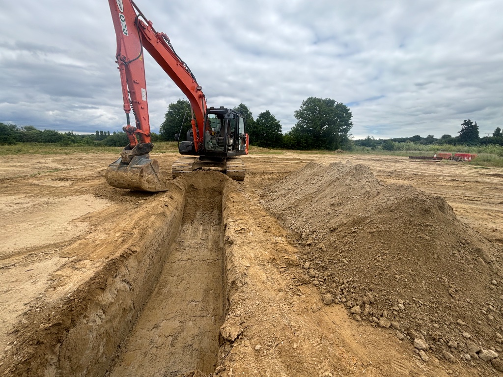 Subsoil Land & Water excavator digging a deep trench for land drainage and water utility installation in East Sussex countryside