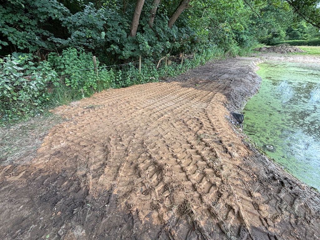 Specialist water management — land drainage upgrades and pond edge earthworks in Battle, East Sussex with corrugated drainage pipe installed into pond bank by Subsoil Land & Water water management contractors