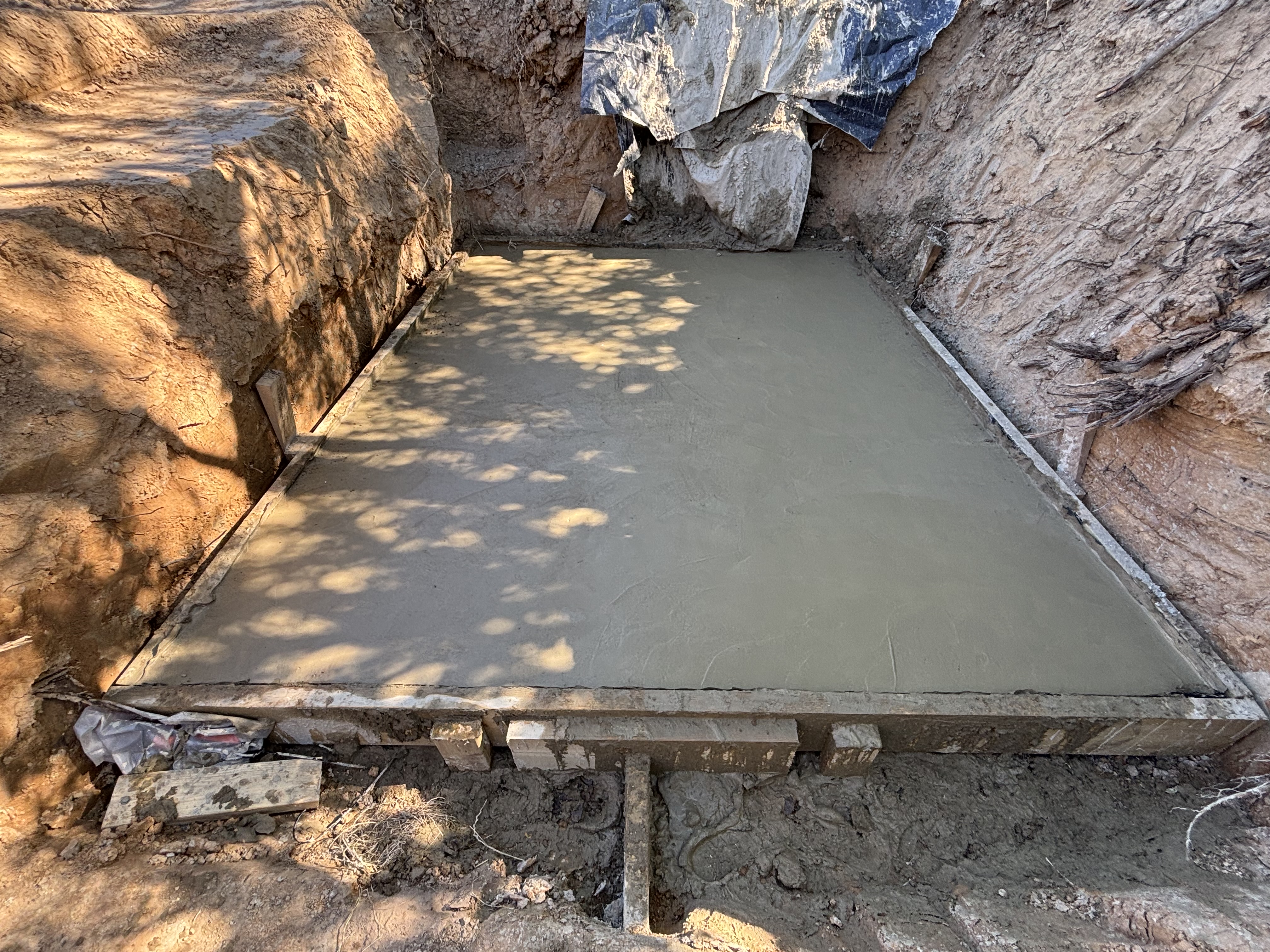 Freshly poured concrete slab foundation in timber formwork within excavated earth pit — concreting in Sussex by Subsoil Land & Water, concrete works and foundations contractors in Battle, East Sussex