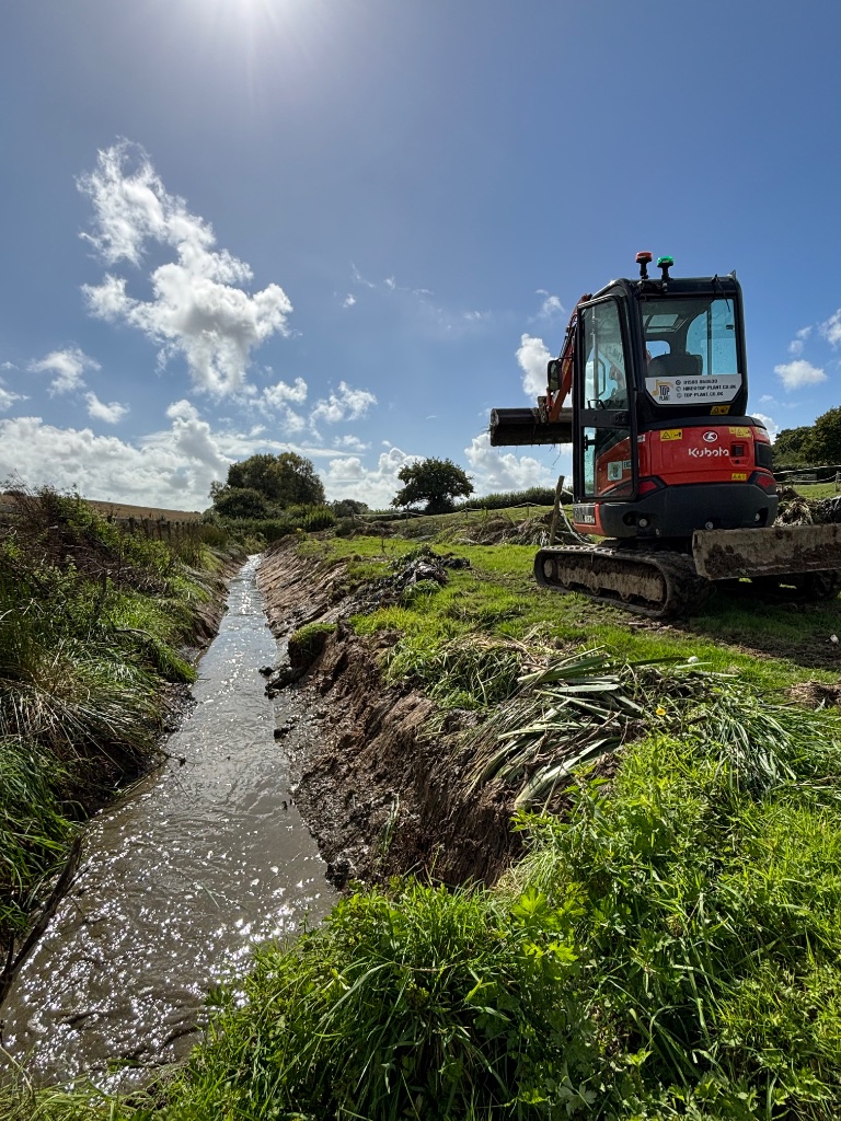 Kubota mini excavator clearing a water drainage trench by Subsoil Land & Water, local independent groundworks and drainage contractors in East Sussex