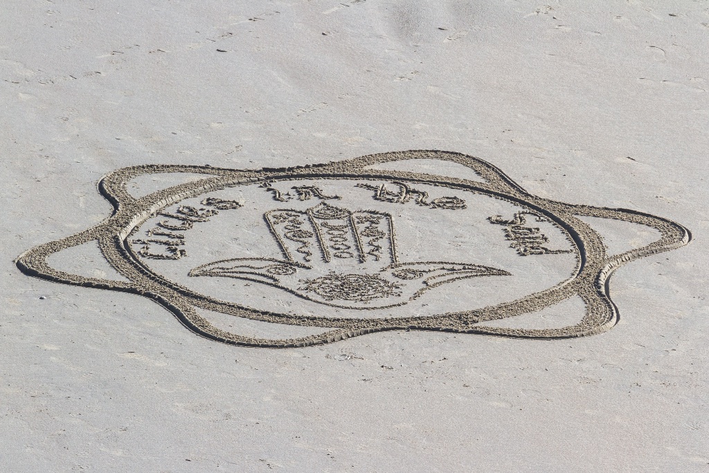 A Hamsa hand symbol drawn into sand