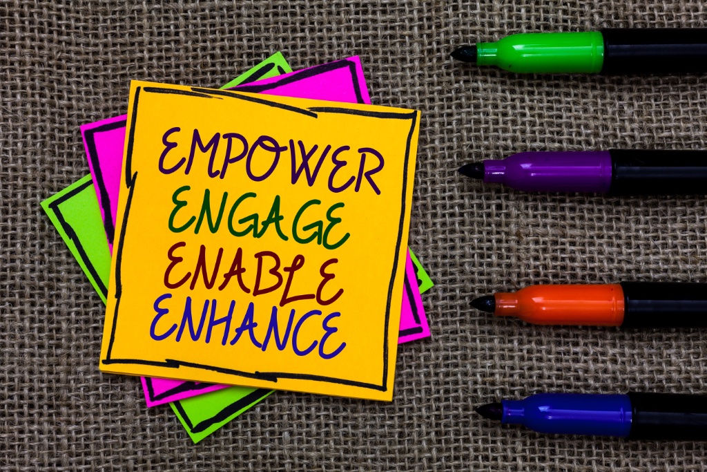 Sticky note with Empower, Engage, Enable, Enhance written in marker