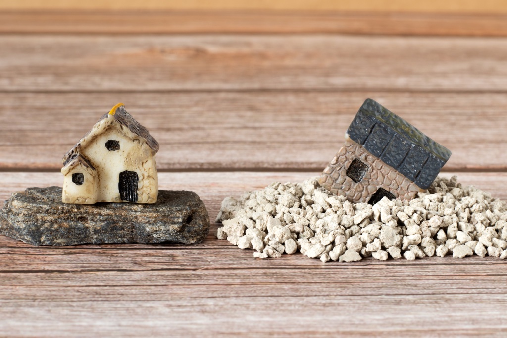 A small cottage figurine resting on solid stone — stability and groundedness