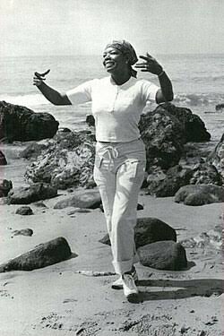 Dr. Maya Angelou dancing with outstretched arms on the shoreline