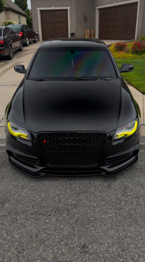 Black Audi with yellow DRL lights freshly detailed in driveway