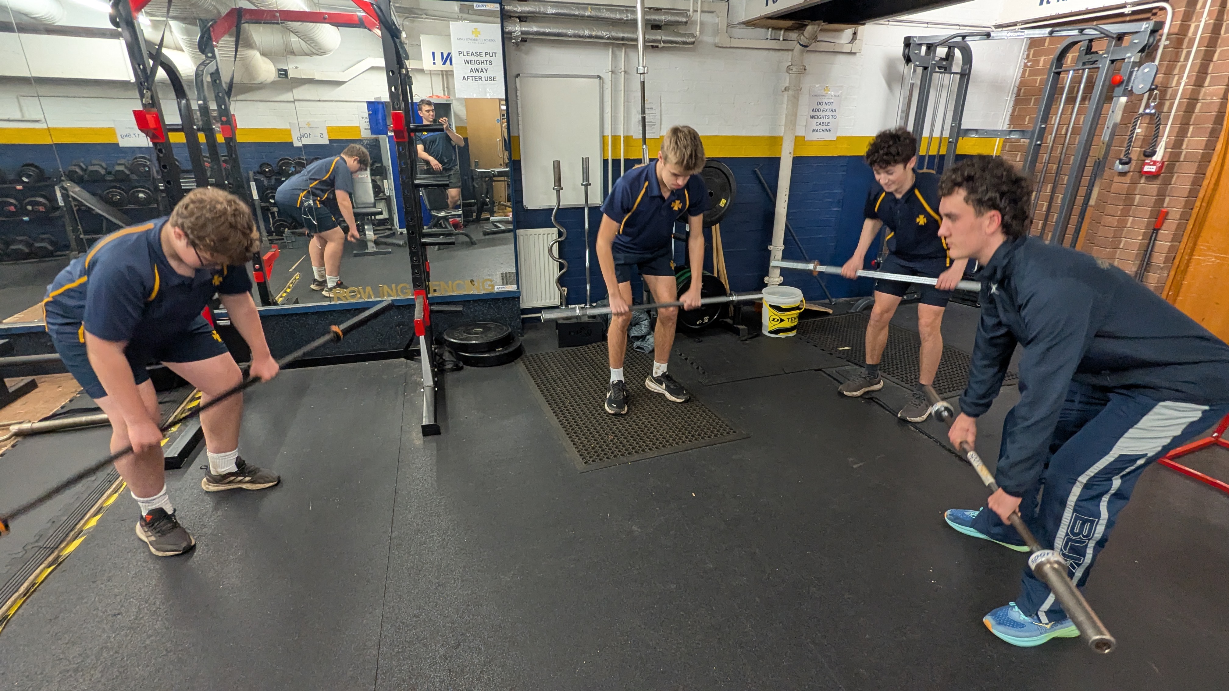 Athletes performing barbell rows during a movement course session at King Edward School