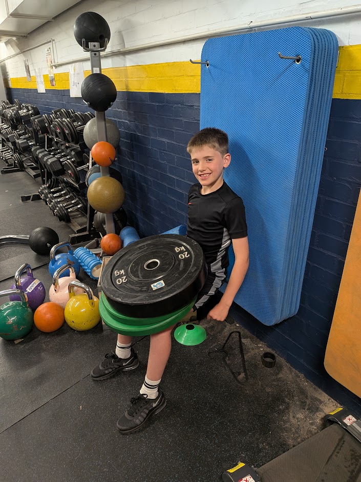 Young athlete holding a weight plate during a one-to-one session