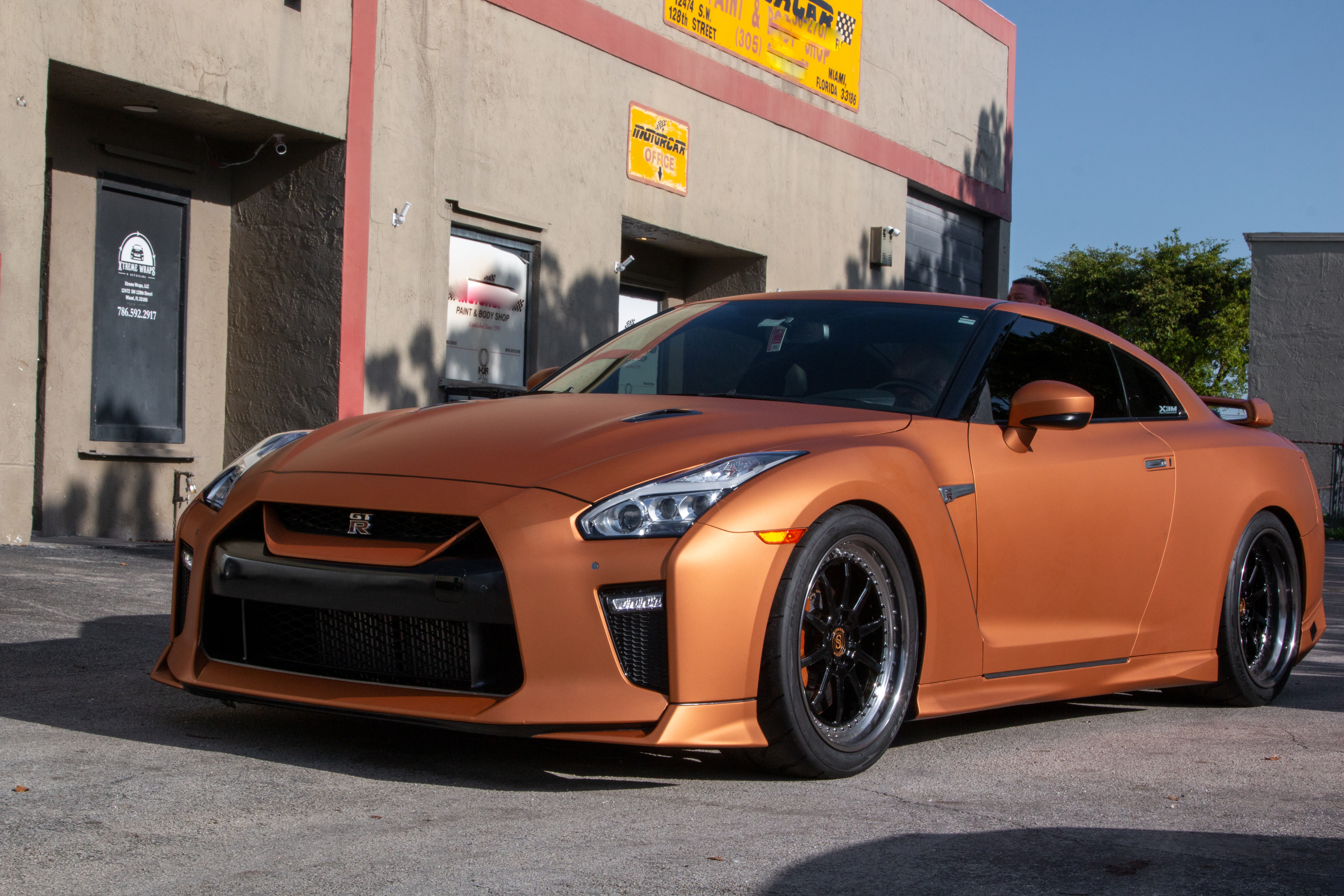 Matte copper-orange Nissan GT-R outside the shop