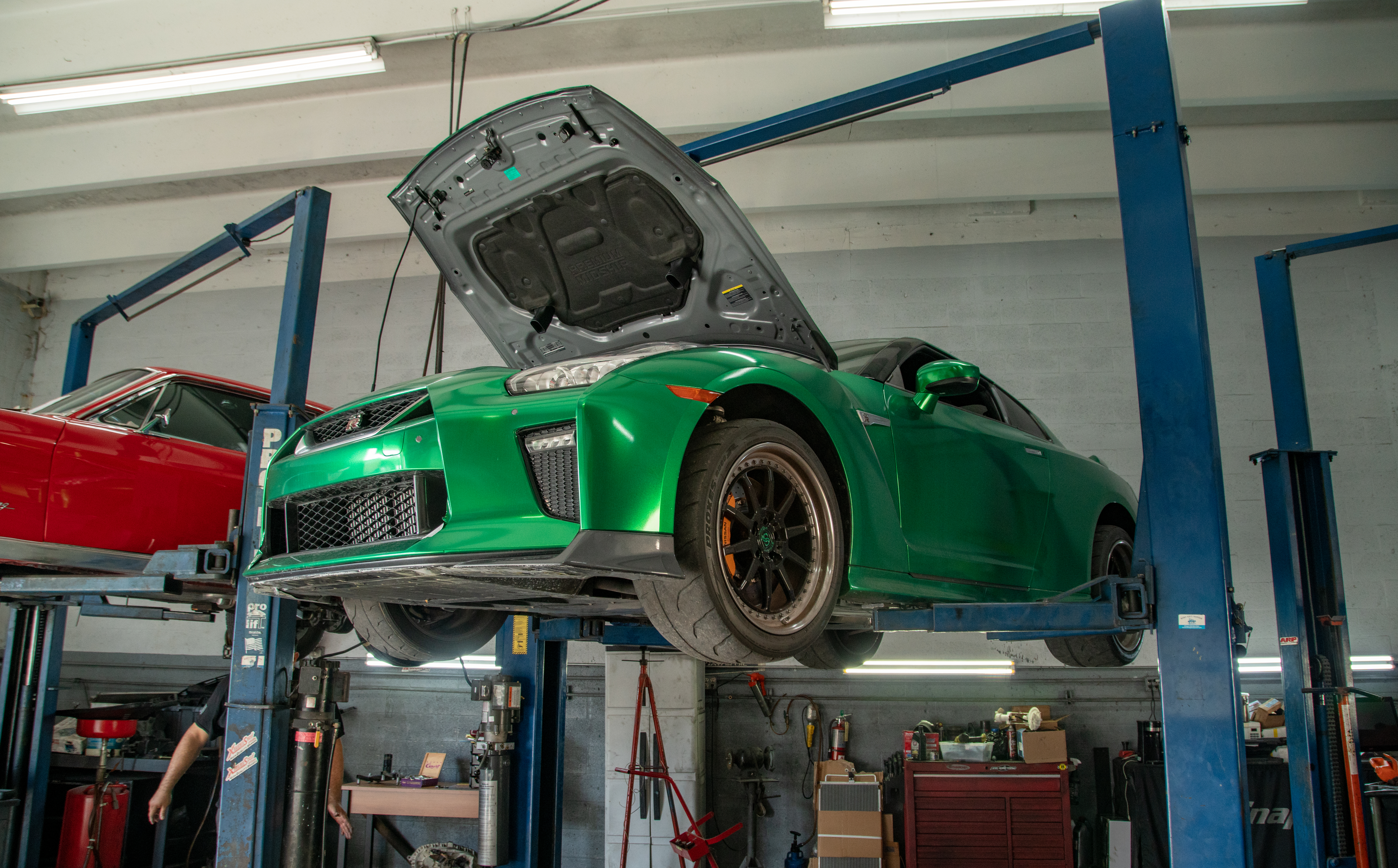 Green Nissan GT-R raised on a two-post lift