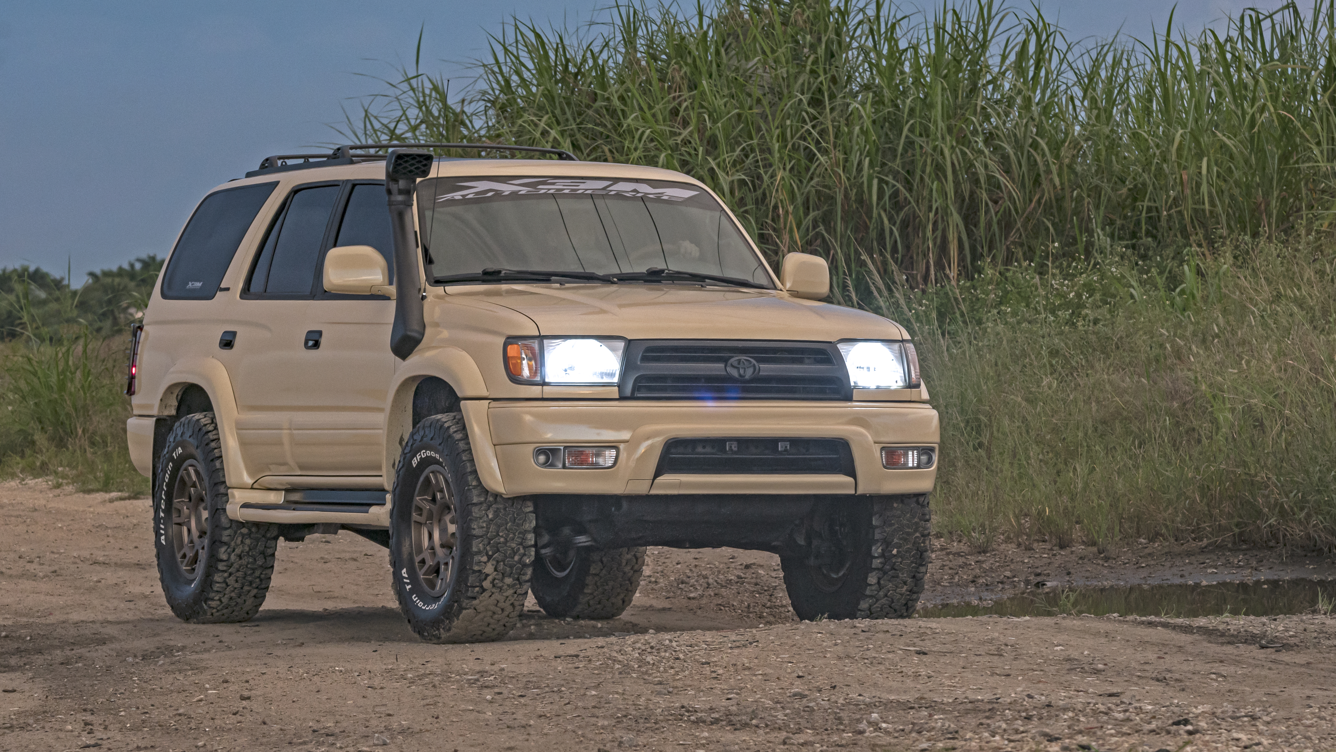 Tan Toyota 4Runner with snorkel and bronze wheels on a dirt trail