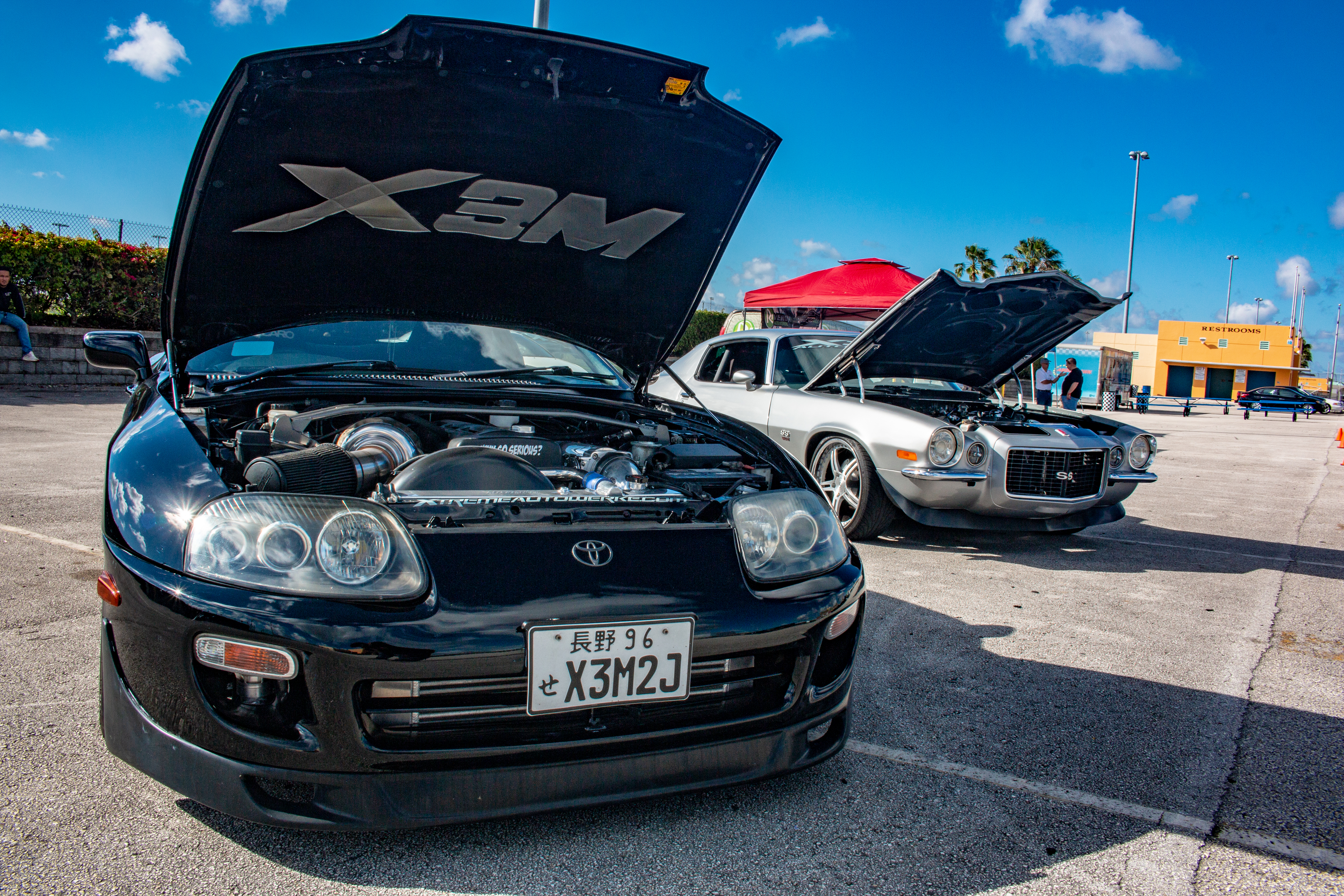 Black Supra and silver Camaro at a car show