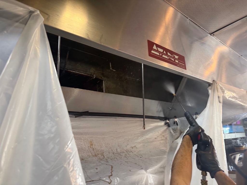 Cleaned commercial kitchen exhaust hood with protective plastic sheeting