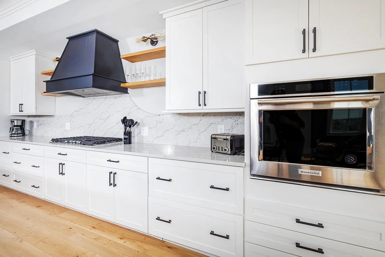 53 Ocean — kitchen with white cabinetry, navy range hood, and integrated wall oven