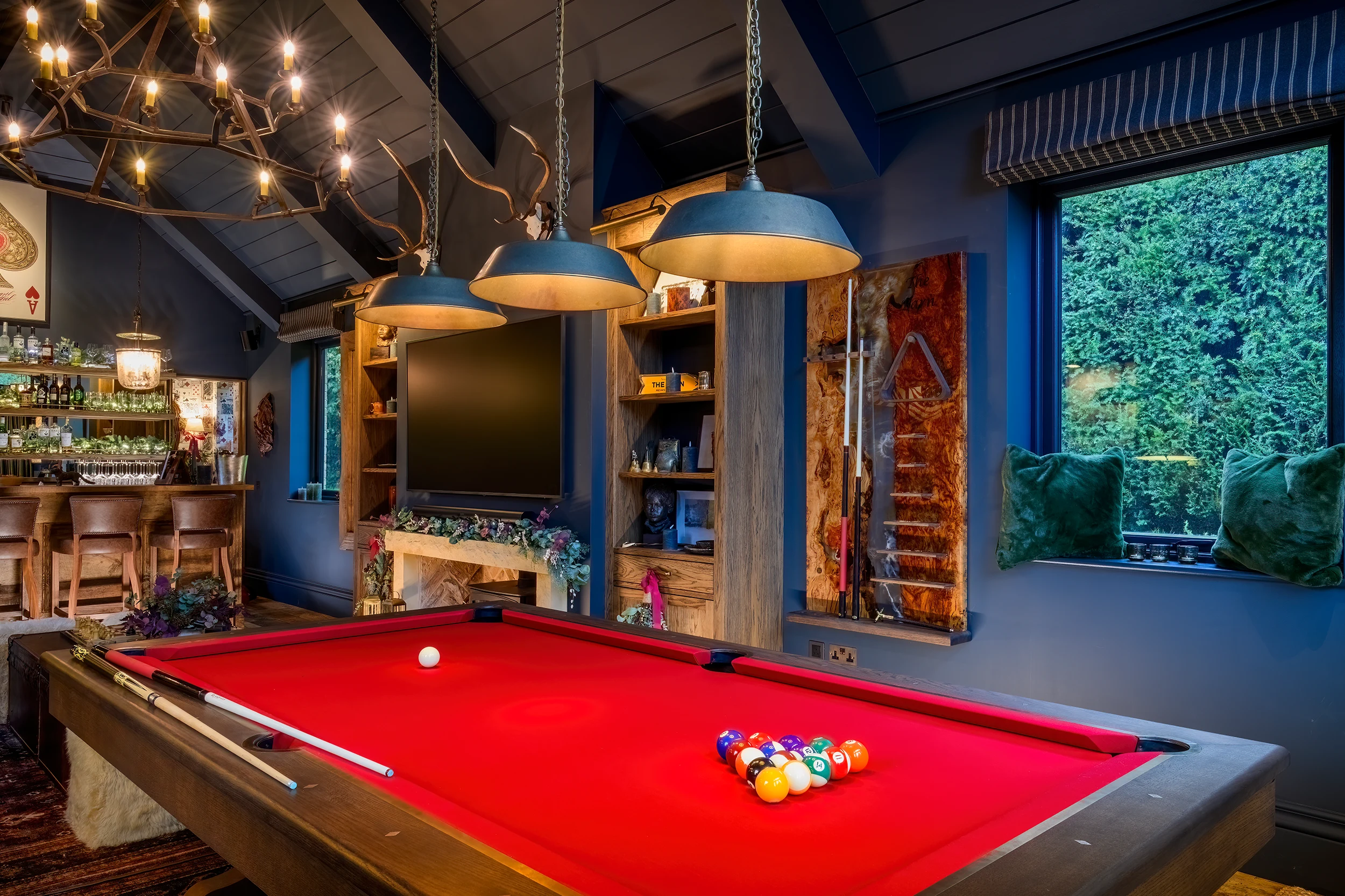 Bespoke pool table in a designed games room with red cloth, bar and built-in shelving by Bruno Boulay