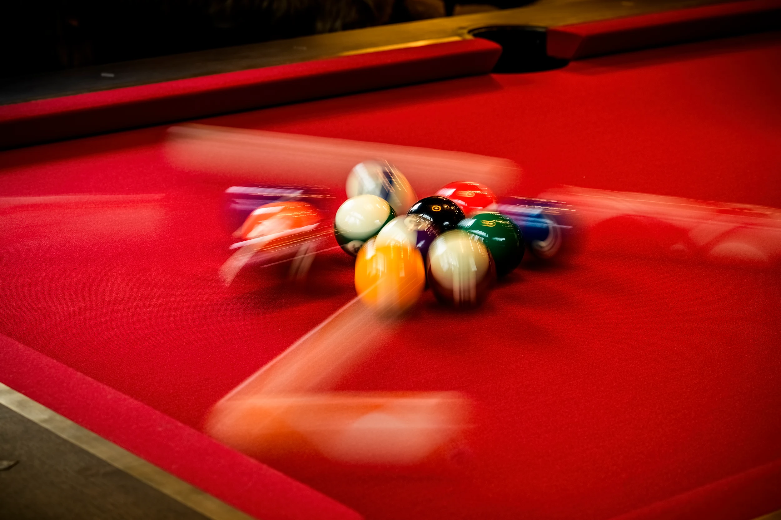 Close-up of pool balls in motion on a red felt bespoke pool table
