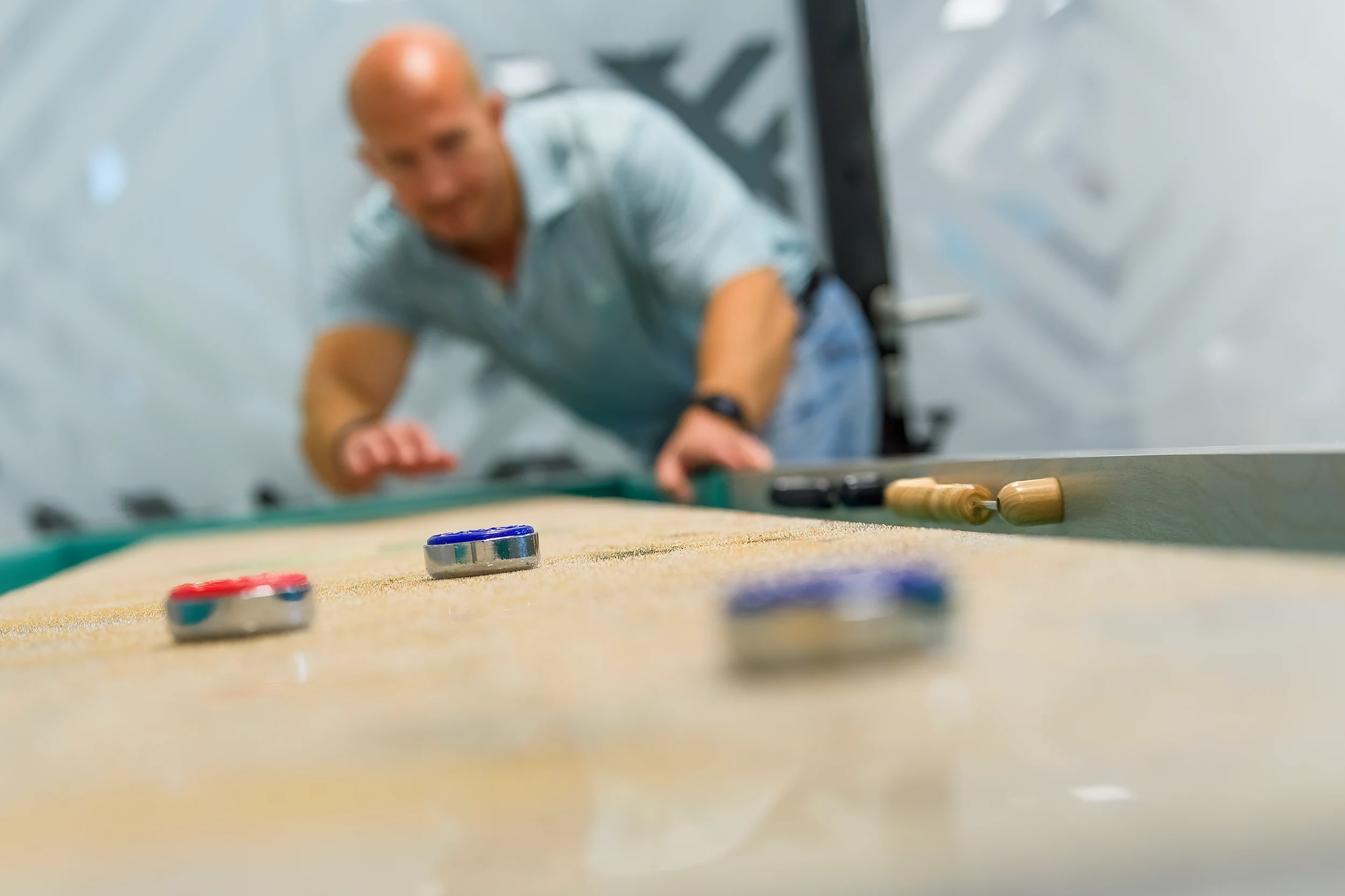 Player sliding a shuffleboard puck on a handmade Bruno Boulay shuffleboard table