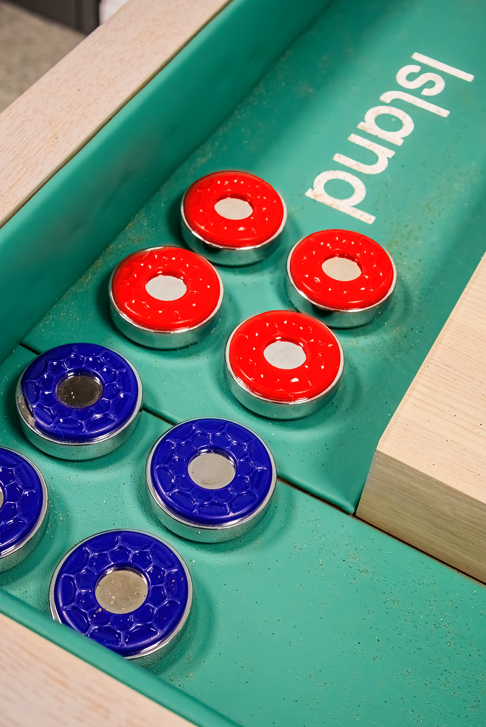 Solid brass shuffleboard pucks on a handmade hardwood table