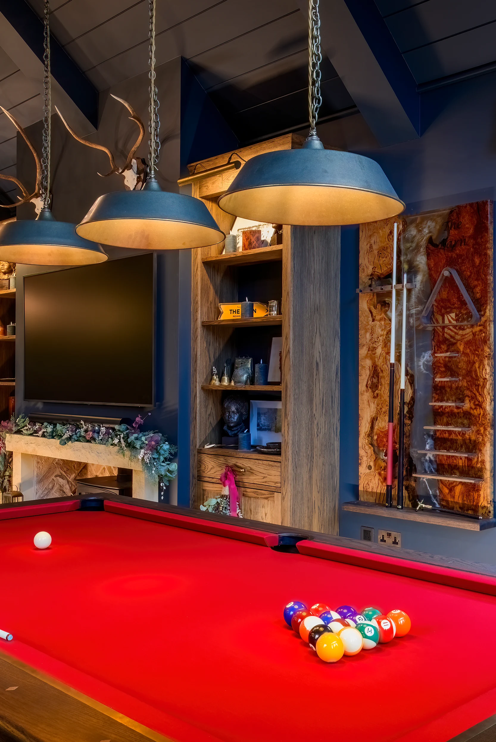 Luxury pool table in a moody games room with bespoke cue rack and shelving