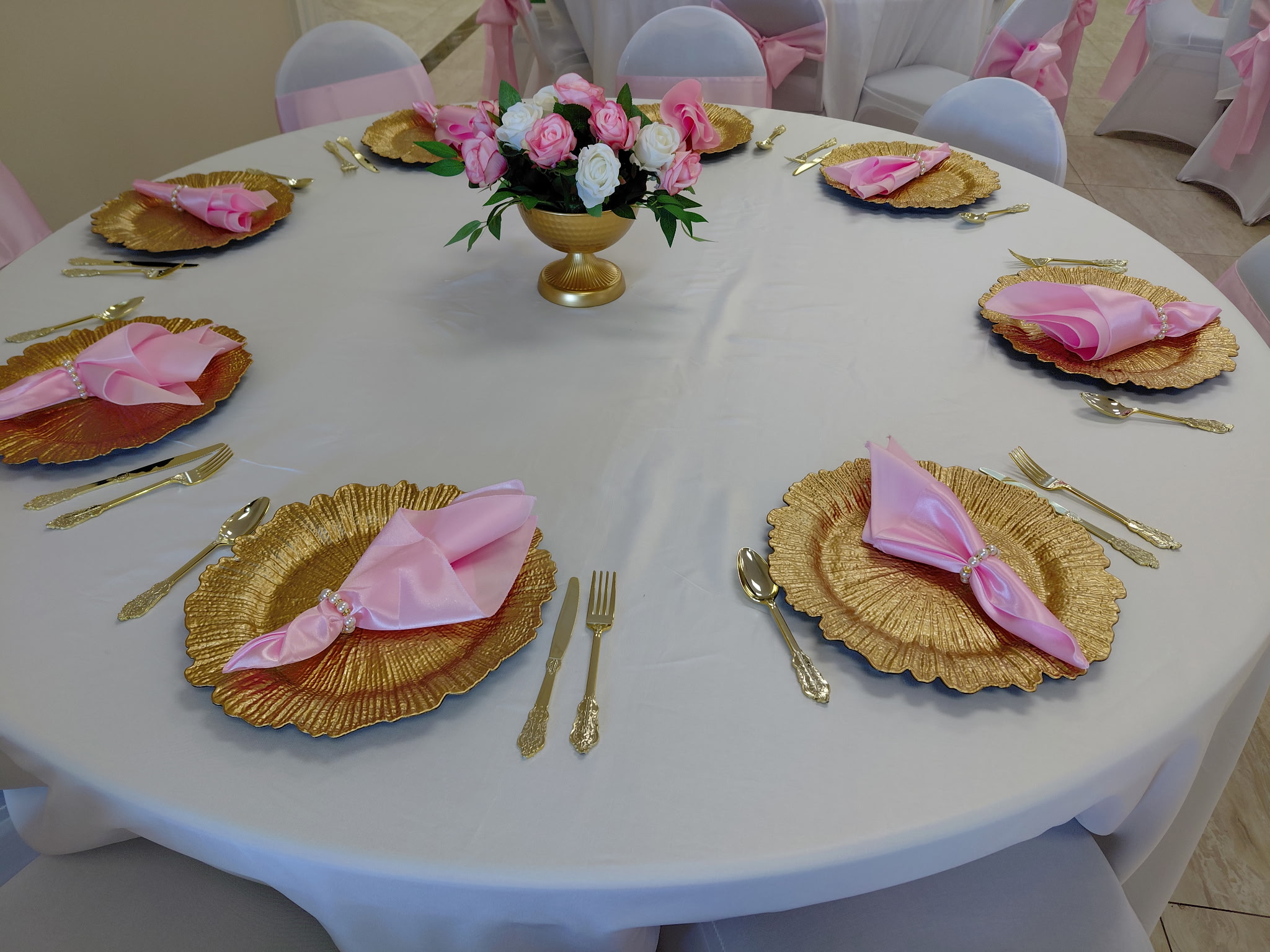 Round table with gold chargers and pink napkins