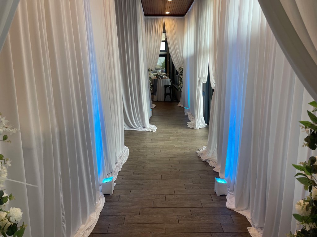 Aisle lined with white drapes and blue uplighting