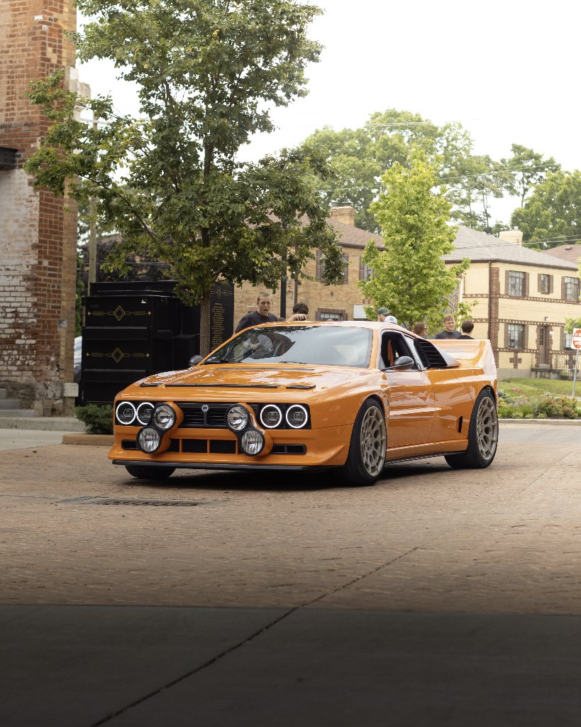 Orange Lancia Delta Integrale rally car parked with rally lights and wide fenders